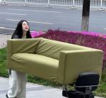 Femme derrière un canapé vert en extérieur
